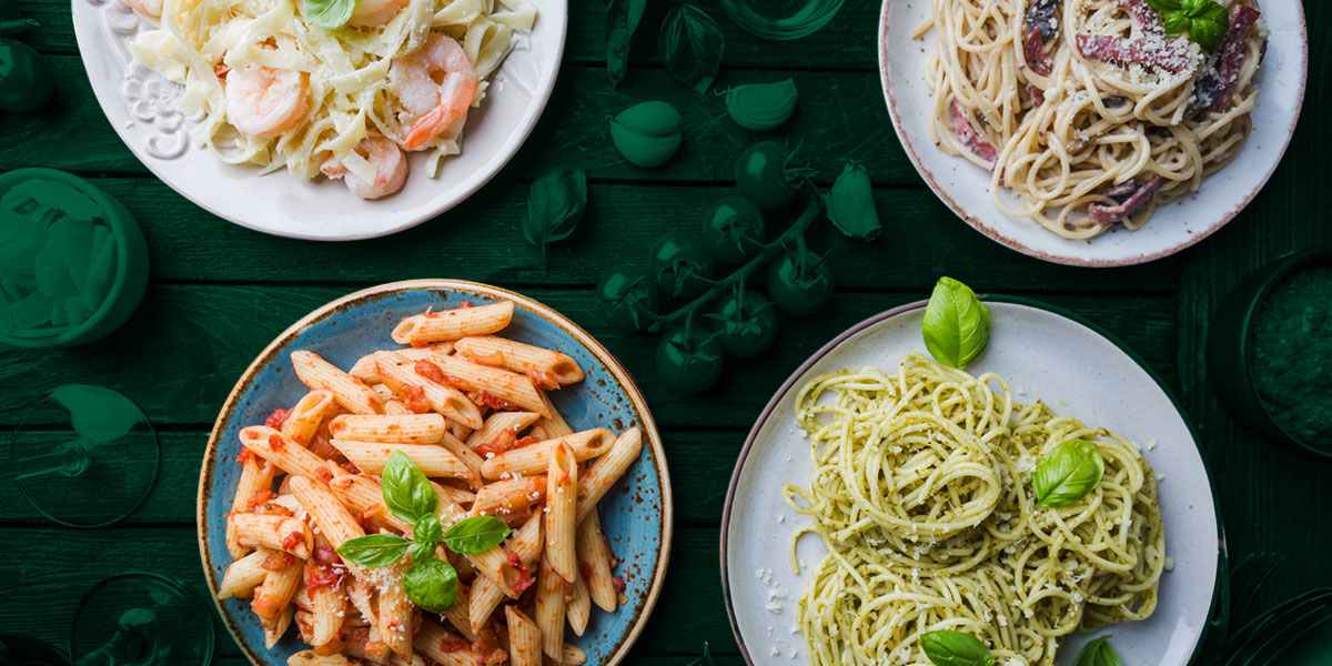 four pasta dishes on a green table